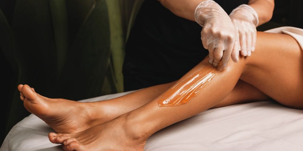 Woman receiving waxing service for her legs.